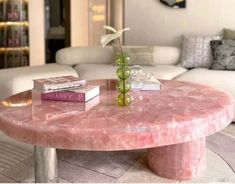 a pink marble coffee table with two books on it and a flower in a vase