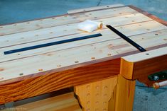 a wooden workbench with two knives and a piece of wood on it's side