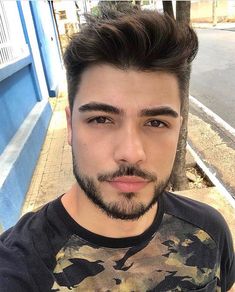 a close up of a person with a goatee and a beard wearing a camo t - shirt