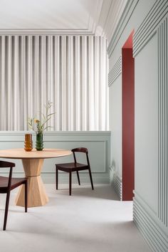 two chairs and a round table in a room with vertical blinds on the wall behind them