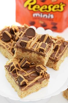 three pieces of peanut butter bars on a plate with reese's bag in the background