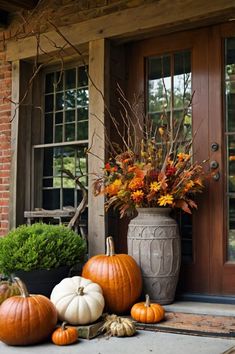 pumpkins and gourds are sitting on the front porch with autumn flowers in vases