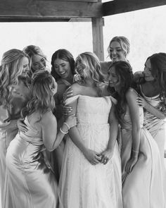 a group of women standing next to each other in front of a window with their arms around each other