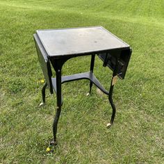 a small black table sitting on top of a lush green field