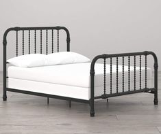 a black metal bed frame with white pillows