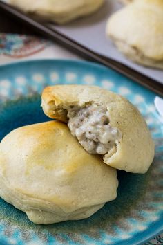 two biscuits are on a blue plate with a spoon in front of them and one is half eaten