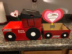 two cardboard boxes with hearts on them sitting on a counter top next to a red truck