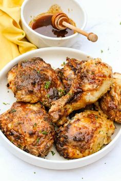 a white plate topped with chicken wings next to a bowl of sauce