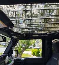 the interior of a vehicle with its sunroof open and trees in the background