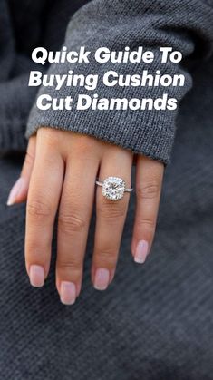 a woman's hand with a diamond ring on top of her finger and the other hand holding an engagement ring