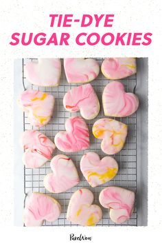 heart shaped cookies on a cooling rack with pink and yellow icing in the shape of hearts