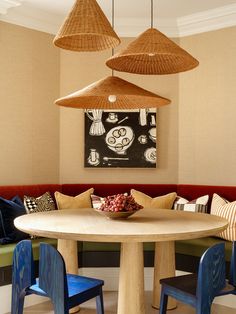 a round table with blue chairs around it in front of a painting on the wall