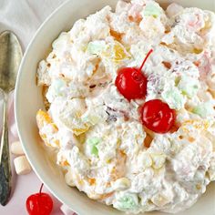 a white bowl filled with fruit salad and cherries