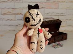 a hand holding a small crocheted voodoo doll