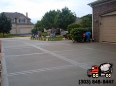 two men are working on the driveway in front of their house