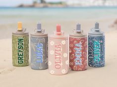 four spray cans sitting on top of a sandy beach