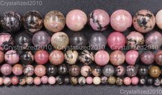 several different types of marble beads on a black surface with white and pink speckles