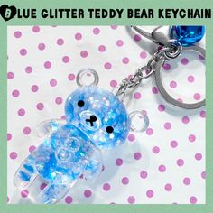 a blue teddy bear keychain on a polka dot tablecloth with the words glue glitter teddy bear key chain