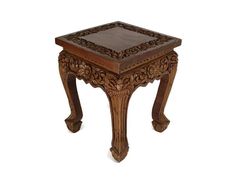 an ornate wooden table with carved designs on it's legs and top, against a white background