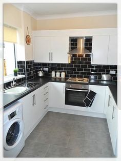 a kitchen with black and white tiles on the walls, counter tops, and appliances