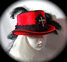 "This Gothic top hat is heavy red velvet wrapped with a black velvet and lace hatband and has a soft black crushed tulle bow & long tails in back. This Victorian style riding hat has black satin roses centered in the back.  There is a silver antiqued Celtic cross centered on a beautiful black lace applique on the front of the crown. A black lace applique rests on the back of the crown's top. The brim & crown edge are trimmed in black satin braid. This hat is loaded with black curled ostrich plumes and measures 23\".  All of the pieces you see in my shop are my original designs and carefully crafted for your pleasure... be sure to contact me for any special requests you may have! For a look at my complete Women's Hat Collection click on this link.... https://www.etsy.com/your/shops/Marcelle Gothic Top Hat With Short Brim For Halloween, Gothic Fitted Brimmed Top Hat, Fitted Gothic Brimmed Top Hat, Gothic High Crown Top Hat For Costume, Red Tall Crown Costume Hat For Party, Gothic Top Hat With High Crown, Gothic Costume Hat With Short Brim, Gothic Adjustable Brimmed Top Hat, Gothic High Crown Top Hat