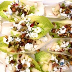 several lettuce wraps with apples, nuts and feta cheese on them sitting on a white plate