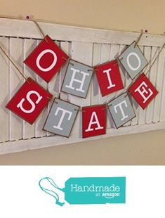 a red and gray sign that says ohio state hanging from a white shuttered wall