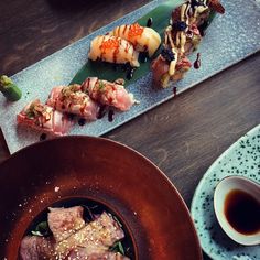 two plates with different types of sushi on them and one plate with chopsticks next to it