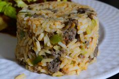 a white plate topped with rice and meat