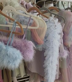 many different colored clothes hang on racks in a store or clothing rack with furs