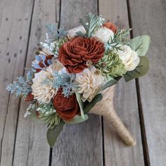 the bridal bouquet is made up of flowers and greenery on a wooden surface