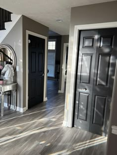 an entryway with stairs and black doors in a house that has been painted gray