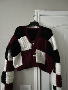 a cardigan sweater hanging on a door with a light switch in front of it