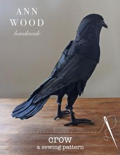 a crow made out of black paper sitting on top of a wooden table