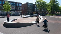 people are walking and riding bikes in the street near an outdoor area with curved concrete steps