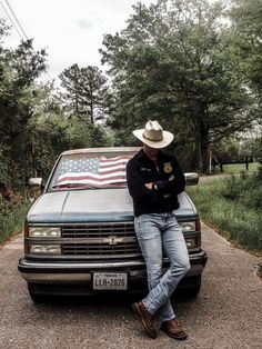 a man sitting on the hood of a truck with an american flag painted on it