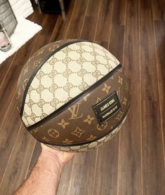 a person holding a basketball in their hand on top of a hard wood floored floor