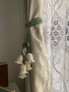 three pom poms hanging from the side of a white curtain in front of a window