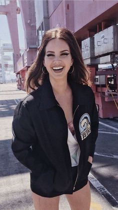 a woman is smiling and posing for the camera with her hands on her hips while wearing a black jacket