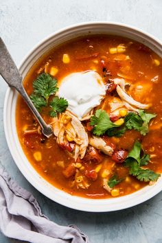 a bowl of chicken tortilla soup with sour cream and cilantro garnish