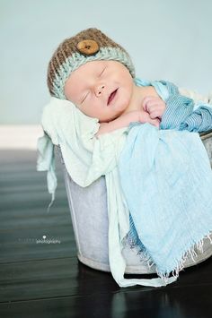 a baby is sleeping in a bucket with a blue blanket on it's back