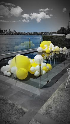 yellow and white balloons are floating in the air next to an empty pool with chairs