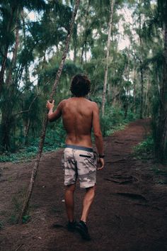 a shirtless man walking down a path in the woods