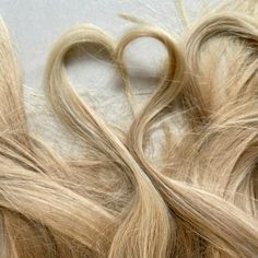 some very long blonde hair laying next to each other on a white surface with one cut in the middle