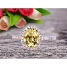 an oval shaped yellow diamond surrounded by white diamonds on a wooden table with flowers in the background