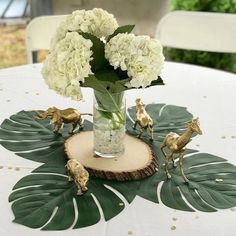 a vase filled with white flowers and giraffe figurines on top of a table