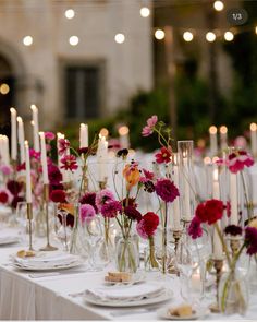 the table is set with candles, plates and flowers in glass vases on it