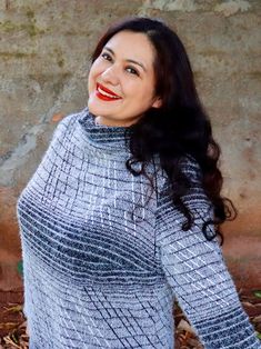 a woman with long black hair wearing a gray and white sweater smiling at the camera