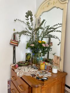 a wooden dresser topped with lots of vases filled with flowers next to a mirror