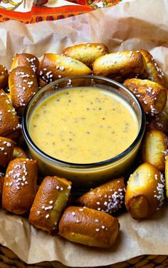 a basket filled with pretzels covered in mustard and dipping sauce next to a bowl of dip